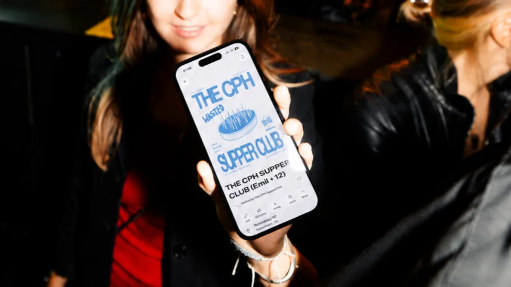 Guest holding a phone showing a CPH Supper Club event on Venga.